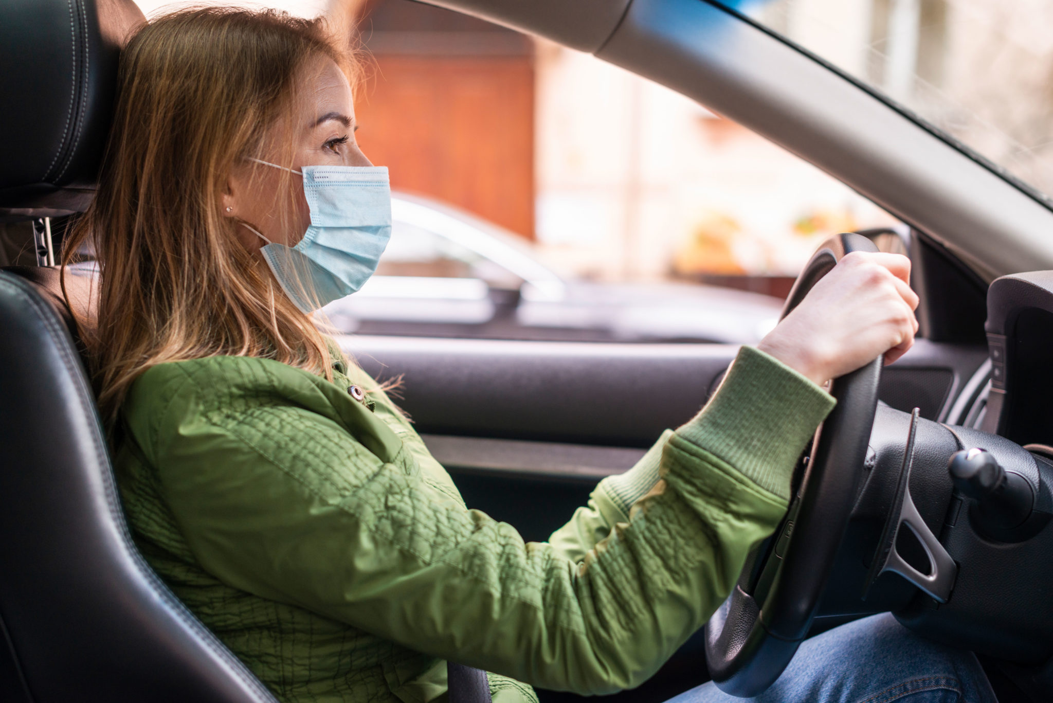 Mujer conduciendo con mascarilla para evitar el contagio por Coronavirus